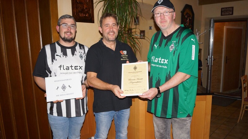 Die Anerkennungsurkunde und ein Schild mit dem Logo des Fanclubs überreichen die beiden Vorsitzenden Stephan Schmelber (rechts) und Christian Breu an den Vereinswirt Matthias Krüger.