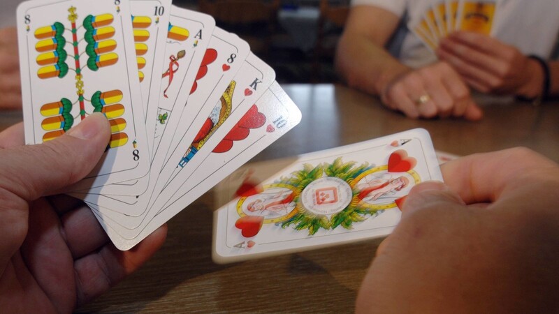 Ein Kartenspieler hält Schafkopf-Spielkarten in der Hand - das Spiel ist bayerisches Kulturgut.