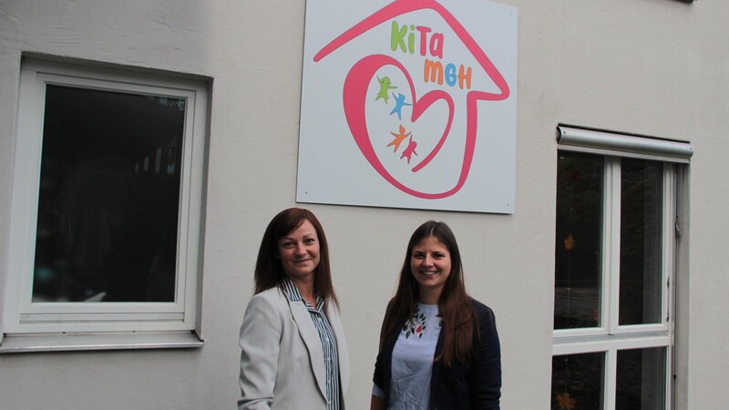 Kindergartenleiterin Kristina Kuzmenko (l.) und Judith Franz von der städtischen Kindergartenverwaltung stehen vor dem Kita-Schild.