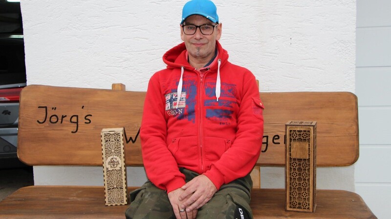 Jörg Wiedemann, alias der "Hoiz Woidi", präsentiert zwei seiner Lieblingsstücke: verzierte Weinflaschenboxen.
