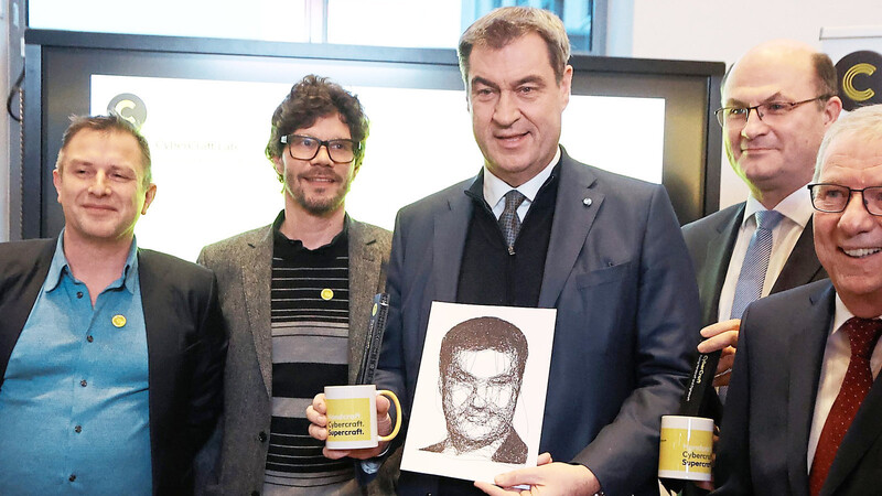 Ministerpräsident Markus Söder (Mitte) erhielt zur Begrüßung in Regensburg von Professor Barlieb (l.) ein vom Computer gezeichnetes Porträt.