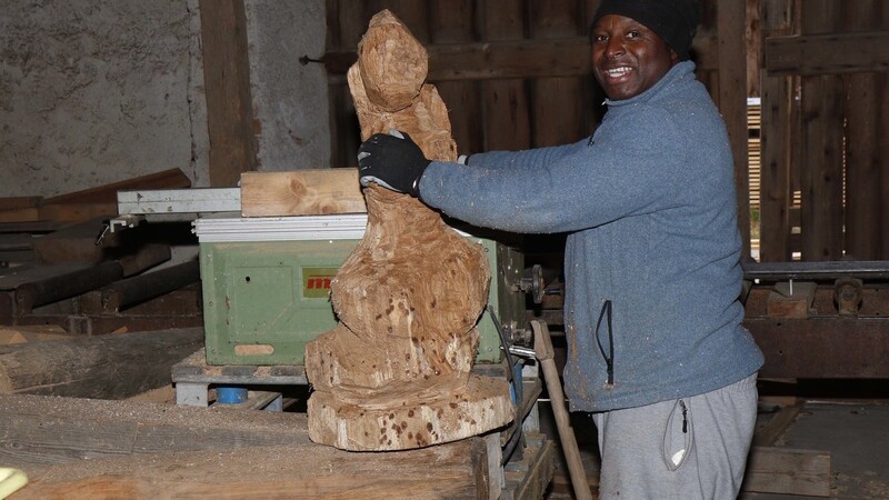 Ifeyani Okolo in seiner Werkstatt: Gerade hat er die Motorsäge weggestellt und rückt sich die noch unfertige Skulptur zurecht.