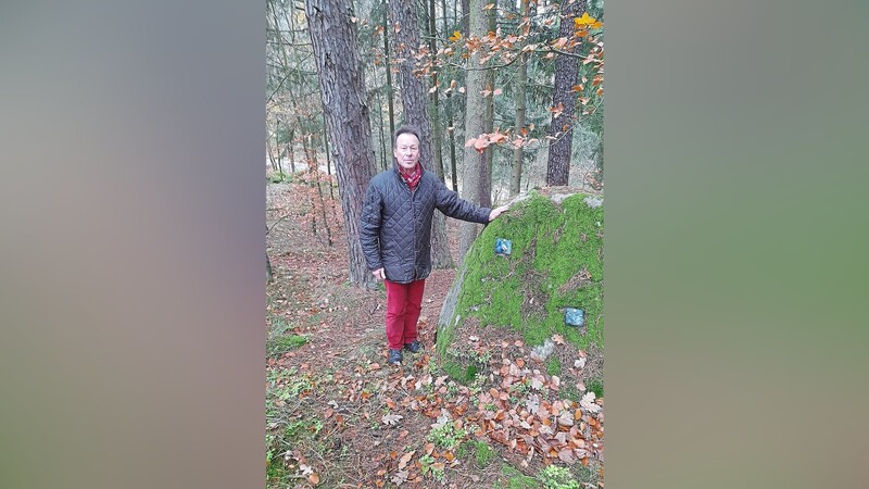 Jürgen Kölbl zeigt eine typische Grabstelle vor einem Findling im Schlosswald. Nur Erinnerungstafeln aus Glas weisen darauf hin, dass hier Menschen begraben liegen.