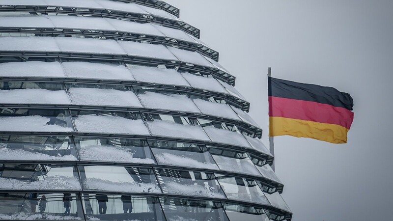 Die Deutschlandfahne weht neben der schneebedeckten Reichstagskuppel im Wind. Der wissenschaftliche Beirat des Wirtschaftsministeriums empfiehlt eine Reform der Schuldenbremse.