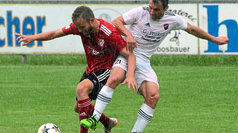 Der Seebacher Waldemar Wagner (weißes Trikot) versucht, im strömenden Regen seinem Gegner den Ball abzuluchsen.