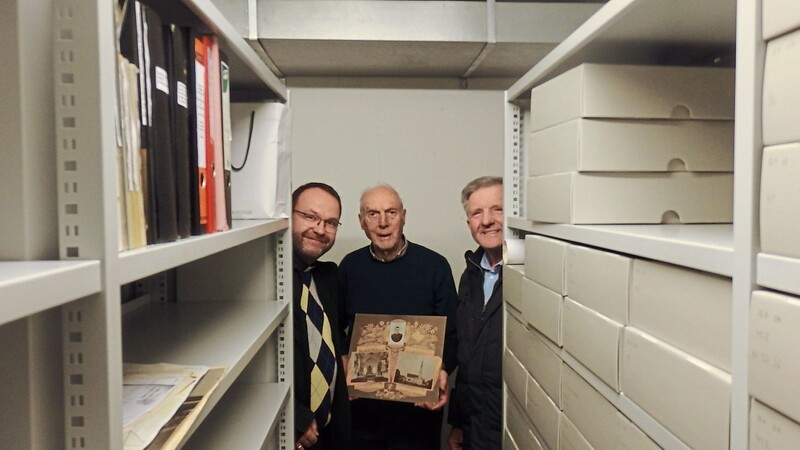 Dekan Stefan Rauscher bei der Entgegennahme der Archivunterlagen, in diesem Fall eine Bilddokumentation, aus den Händen von Adolf Widmann und Hans Penger (v. l.).