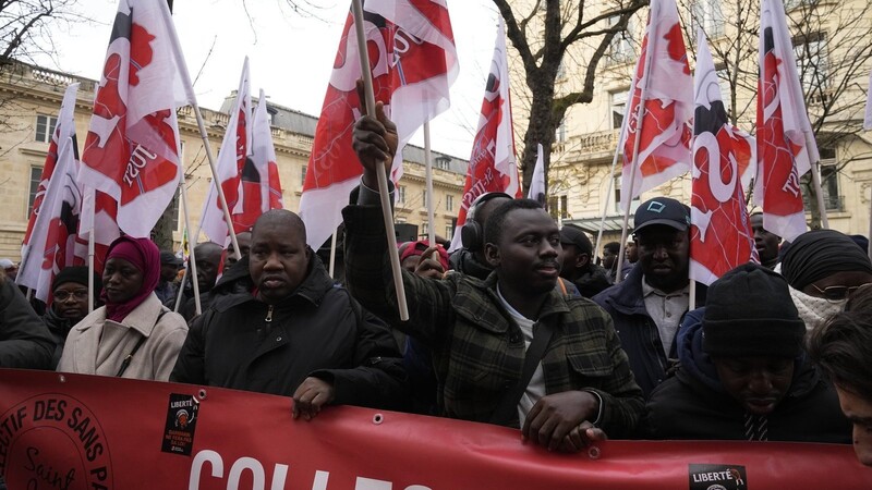 Migranten stehen vor der Nationalversammlung in Paris. Mit einem neuen Migrationsgesetz will Frankreich den Umgang mit Asylbewerbern verschärfen, zugleich aber illegalen Beschäftigten in Mangelberufen eine Bleibeperspektive eröffnen.