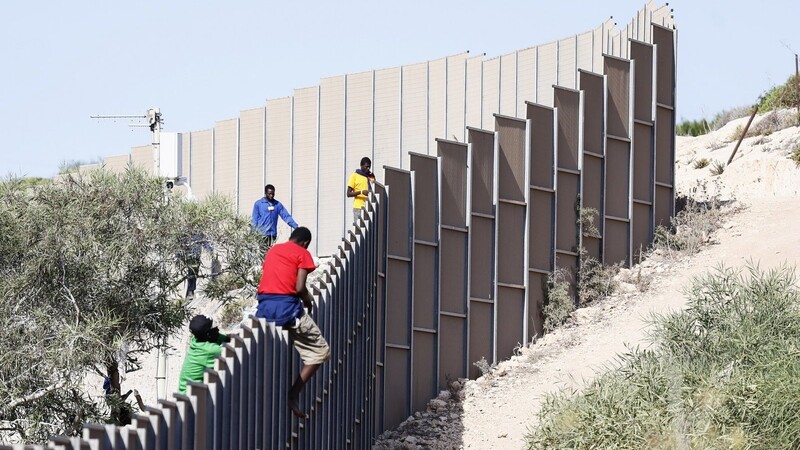 Migranten klettern über einen Zaun auf der Insel Lampedusa.