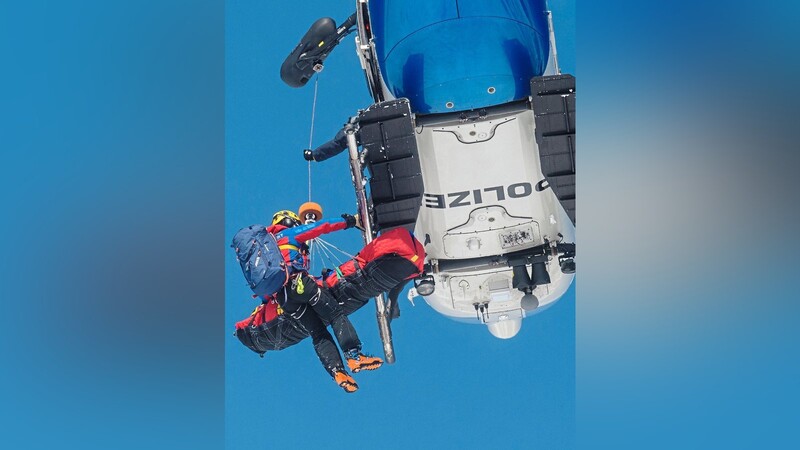 Ein Bergwachtler und ein aus dem Schnee gerettetes "Opfer" werden bei einer Lawinenübung in einen Polizeihubschrauber gezogen