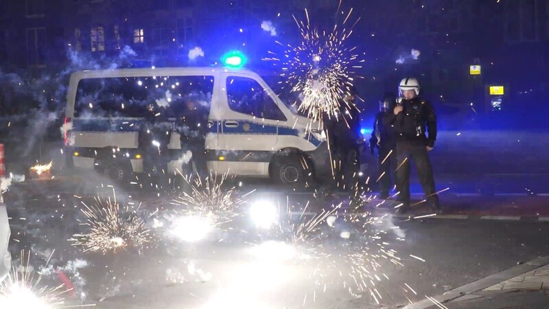 Polizeibeamte stehen am Silvesterabend hinter explodierendem Feuerwerk.
