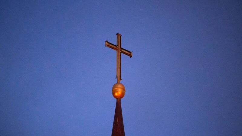Ein Kreuz steht auf der Kirchturmspitze einer evangelischen Kirche. Seit Jahrzehnten hat es auch dort sexualisierte Gewalt gegeben. Eine Studie offenbart nun das Ausmaß.