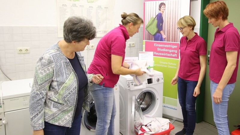 Schulleiterin Ingeborg Hüllbusch (links) erläutert den Studierenden das richtige Beladen einer Waschmaschine. Einer der Lerninhalte besteht in der rationellen und umweltbewussten Wäschepflege.