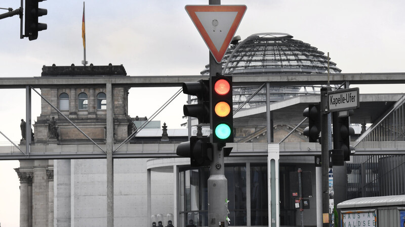 Eine Ampel, an der für einen Moment die Farben Rot, Gelb und Grün gleichzeitig leuchten. Hier berät der Bundestag final über den Haushaltsplan der Ampel-Koaltion. Für 2024 soll die Schuldenbremse aussetzen. Zwei der drei Parteien wollen jedoch eine Reform.
