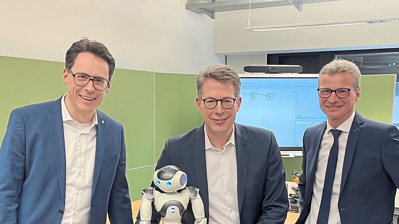 Der bayerische Staatsminister für Wissenschaft und Kultur, Markus Blume (Mitte), Landrat Bernd Sibler (r.) und Oberbürgermeister Dr. Christian Moser mit einem KI-Roboter.