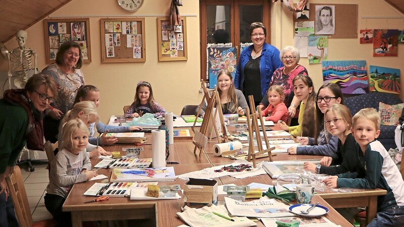 Malkasten, Pinsel, Schwamm und noch mehr künstlerisches Material liegt auf dem Tisch vor den Kindern. Mit viel Spaß sind sie dabei, Renate Fuchs (rechts) steht dabei seit 25 Jahren mit Rat und Tat zur Seite.