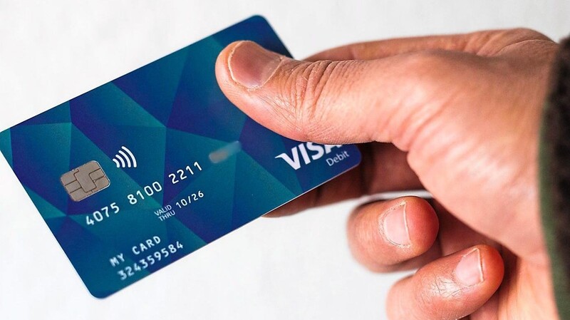 Ein Geflüchteter hält eine Debitkarte in der Hand. Die Pläne zur Bezahlkarte werden konkret.