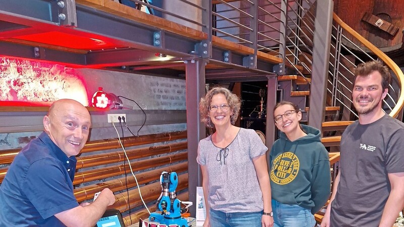Prof. Dr. Claudia Meitinger (3. von rechts) von der Fakultät für Elektrotechnik der Technischen Hochschule Augsburg und ihr Team überwachen Erich Rohrmayer (links), als er gegen deren Kartenspiel-Roboter eine Patie Watten spielt.