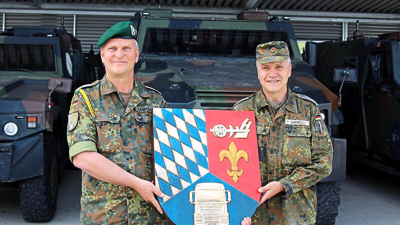 Kompaniefeldwebel Peter Lagerbauer (l.) und Ernst Gammel, Leiter des Kraftfahrausbildungszentrums Feldkirchen, mit dem Wappen des Zentrums.