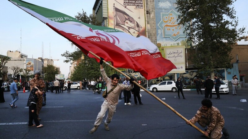 Demonstranten schwenken eine riesige iranische Flagge bei einer anti-israelischen Versammlung vor einem anti-israelischen Banner an der Wand eines Gebäudes auf dem Felestin (Palästina) Platz. Immer mehr Politiker fordern die Abkehr vom Iran.