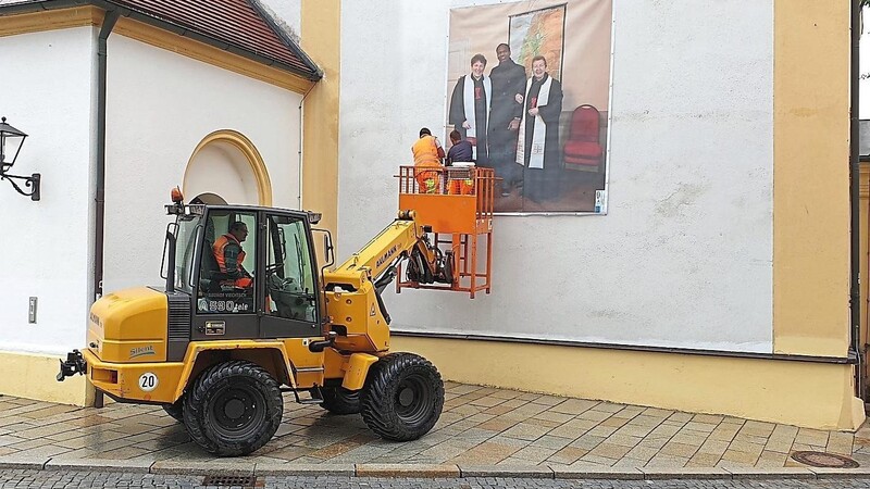 Ein Bauhoftrupp bringt eines der Großbanner an der Kirchenfassade in Viechtach an.