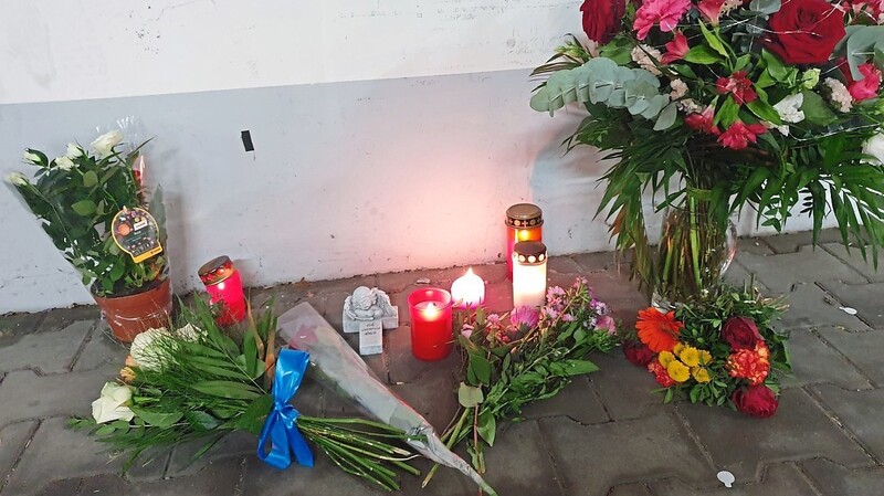 Blumen und Kerzen stehen auf dem Parkplatz, an dem die tote Frau im Kofferraum ihres Autos aufgefunden wurde.