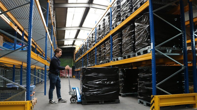 Felix Schratzenstaller hebt eine 1,3 Tonnen schwere Gitterbox mit Sandsäcken aus dem Regal. Etwa 8000 sind bereits abgefüllt.