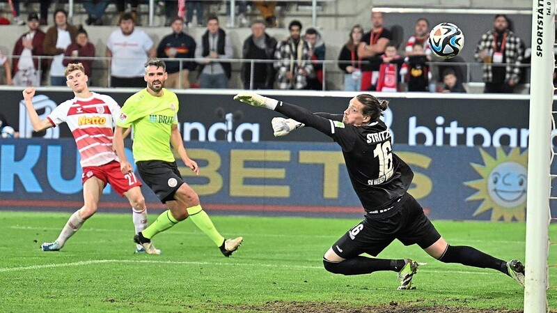 Dominik Kother (l.) zirkelt den Ball gut zehn Minuten vor Schluss an Torwart Florian Stritzel vorbei ins Netz - und lässt den SSV Jahn Regensburg damit weiter von der Rückkehr in die 2. Bundesliga träumen.