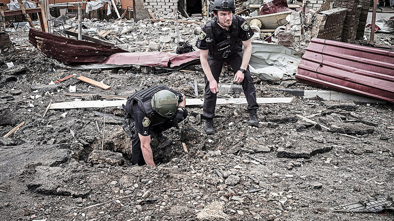 Militärs inspizieren einen Bombenkrater zwischen Trümmern nach einem Bombeneinschlag in einem Wohnviertel in Charkiw. Zum Schutz der Bevölkerung gibt es nun die Erlaubnis, auch mit deutschen Waffen auf das angrenzende russische Gebiet zu feuern.
