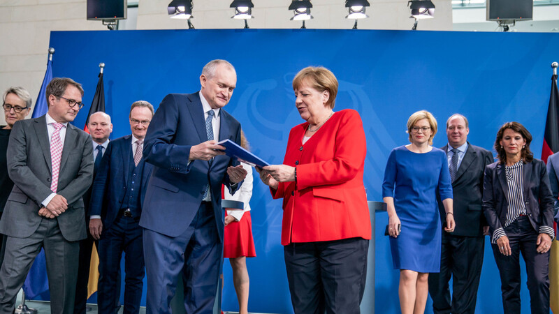 Der Vorsitzende des Sachverständigenrats, Christoph M. Schmidt, übergibt Kanzlerin Angela Merkel (CDU) das Sondergutachten zur CO2-Bepreisung.