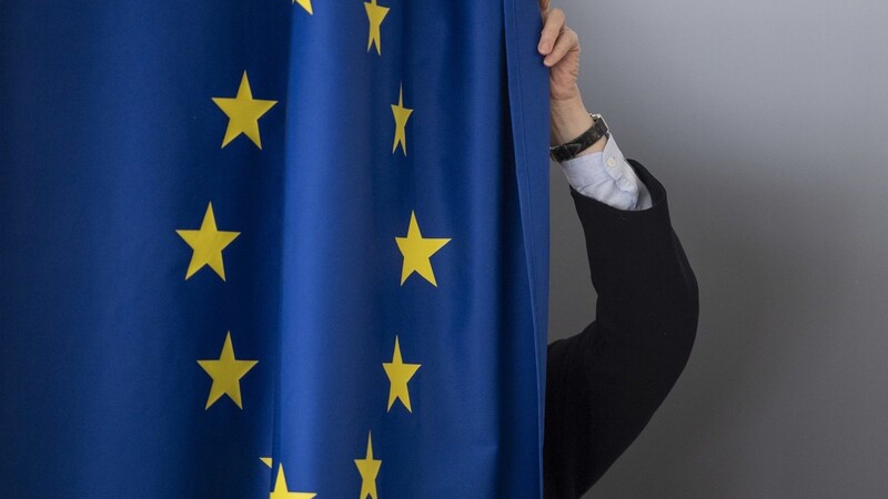 Eine Frau zieht sich zum Ausfüllen ihrer Briefwahlunterlagen für die bevorstehende Europawahl in die mit einer Europaflagge versehene Wahlkabine zurück.