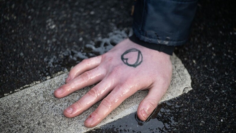 Ein Klimaaktivist hat sich mit der Hand auf den Asphalt geklebt.