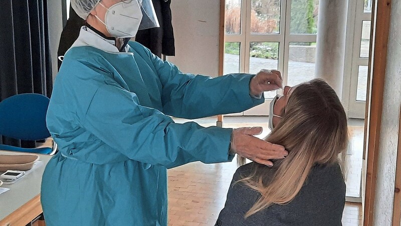 Eine Frau lässt sich von einer Mitarbeiterin ein Wattestäbchen in die Nase einführen.