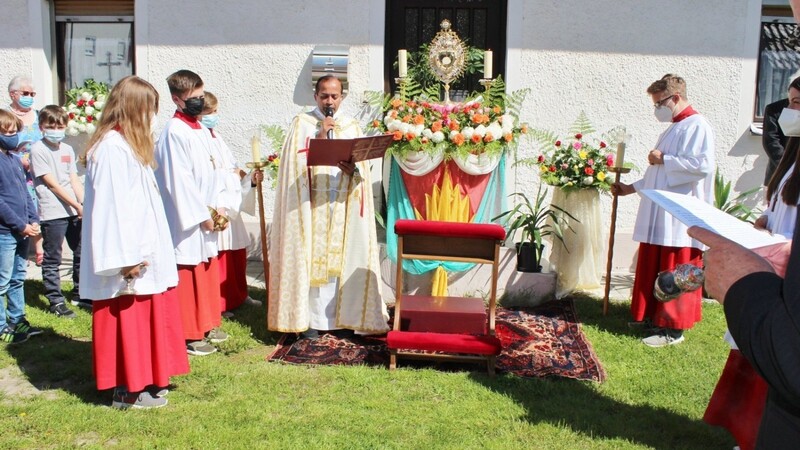 Pater Michael Raj verkündet das Evangelium. Die indischen Schwestern haben ihren Altar kunstvoll und farbenfroh vor ihrer Haustüre hergerichtet.
