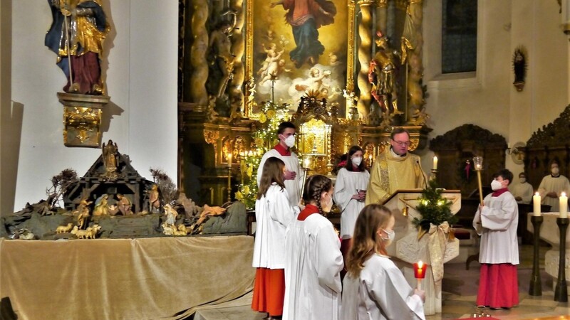 Stadtpfarrer Karl-Heinz Seidl beim feierlichen Weihnachtsevangelium an Heiligabend, links die nach vorne geholte Kirchenkrippe.