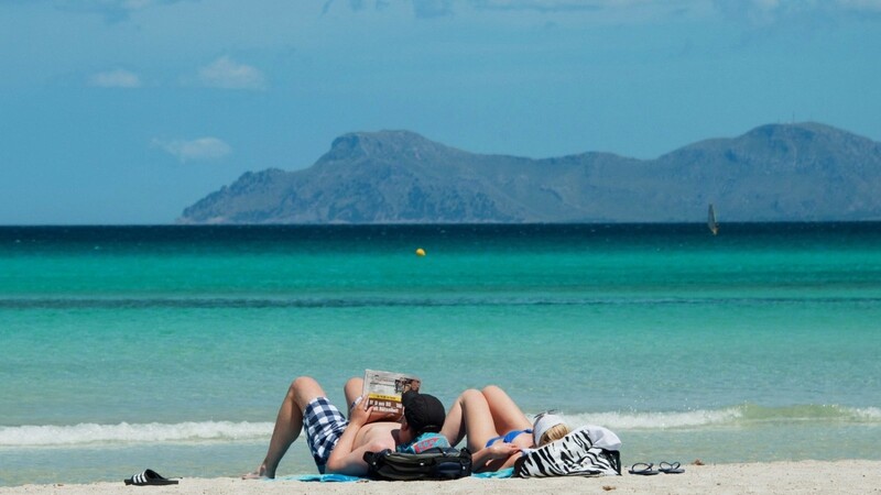 In diesem Jahr ein ferner Traum: Urlauber liegen am Strand an der Platja de Muro im Norden der Mittelmeerinsel Mallorca.