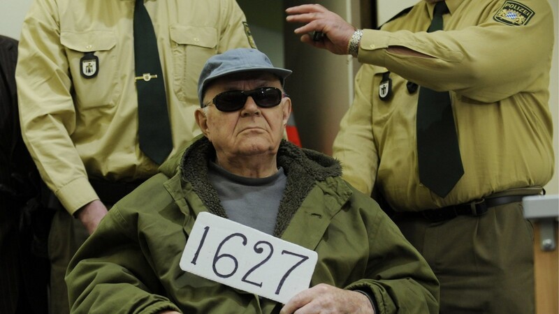 Die Zahl 1627, die John Demjanjuk 2011 in einem Verhandlungssaal des Landgerichts München in Händen hält, bezieht sich auf die Nummer einer KGB-Akte, die ihn angeblich entlastet.