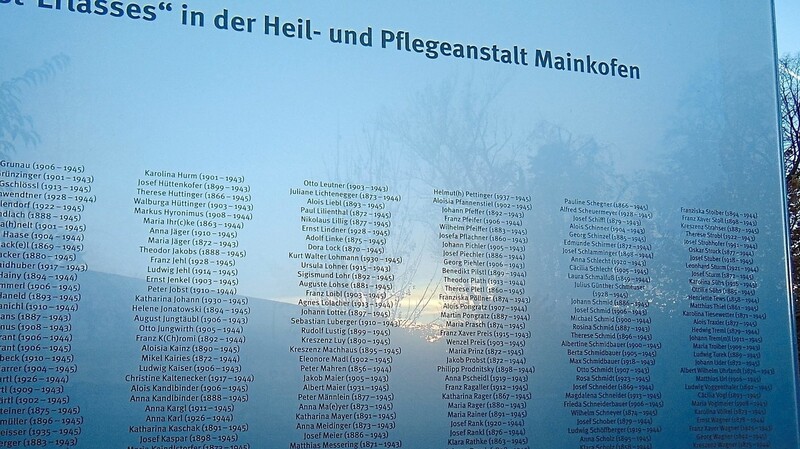 Die untergehende Sonne macht Hunderte von Namen auf der gläsernen Gedenktafel für die Ermordeten sichtbar.