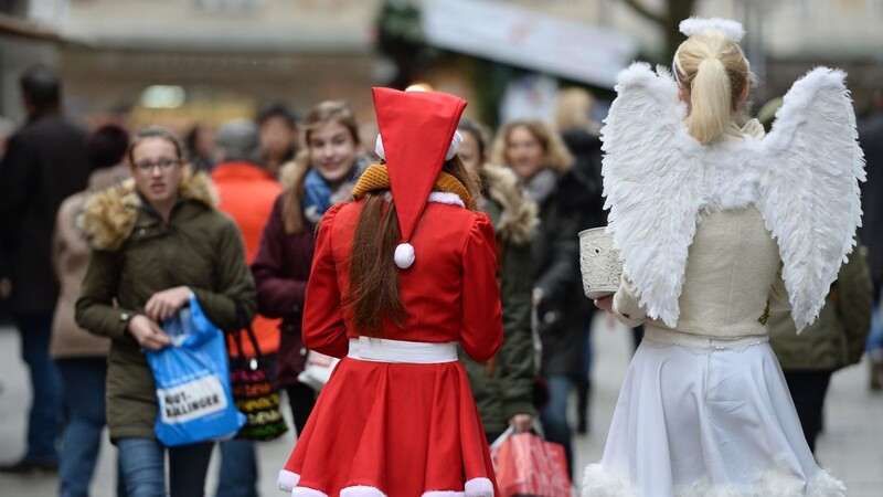 Zwei als Weihnachtsmann und Engel verkleidete Frauen verteilen in Münchens Innenstadt Lebkuchen.