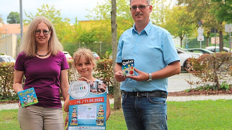 Birgit und Bernhard Fuchs mit ihrer neunjährigen Tochter Sofia, die das Plakat für "Stadt-Land-Spielt!" am 10. und 11. September auf der "Falterhütte" in die Kamera hält.