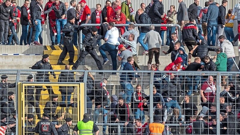 Polizisten mit gezücktem Schlagstock stürmen nach Schlusspfiff in den Gästeblock des Grünwalder Stadions.