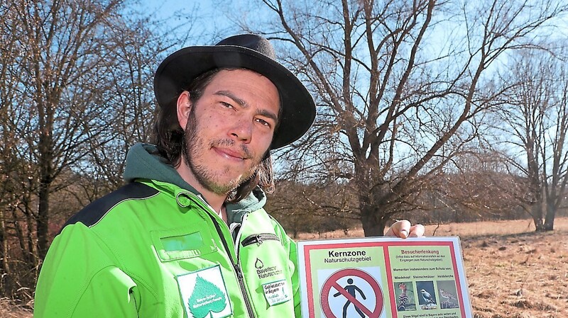 Gebietsbetreuer Fabian Hertrich mit einem der Hinweisschilder, die im Naturschutzgebiet nun aufgestellt sind.
