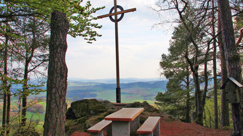 Das neue Gipfelkreuz auf dem Burgstall oberhalb von Gschwand mit der Sitzgruppe davor.