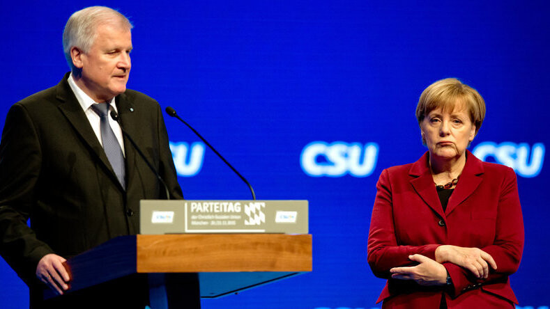 Mit versteinerter Miene hört sich die Kanzlerin an, wie CSU-Chef Seehofer auf offener Parteitagsbühne die Gegenposition zu ihr bezieht.