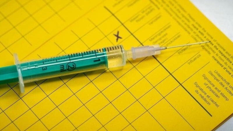 Eine Spritze liegt auf einem Impfpass.