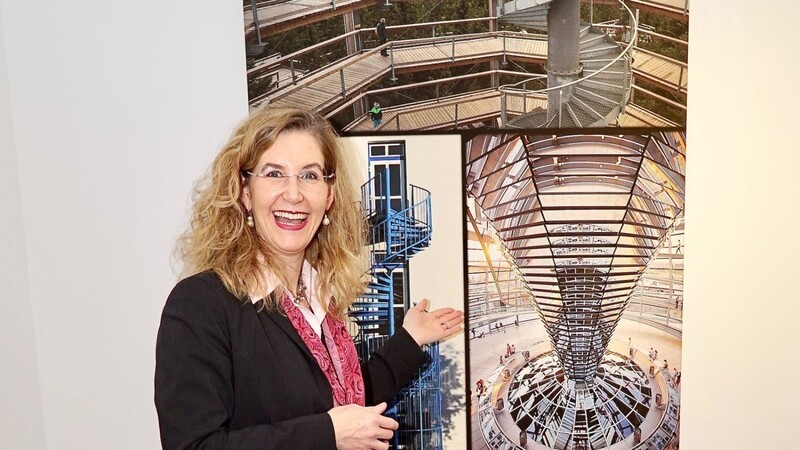 Die Freude über die Fotoausstellung der Fotofreunde spiegelt sich im Gesicht von Hotelmanagerin Nicole Weber-Bürger im Hotel Theresientor, die vor einer Collage zum Thema "Was uns nach oben bringt ..." steht.