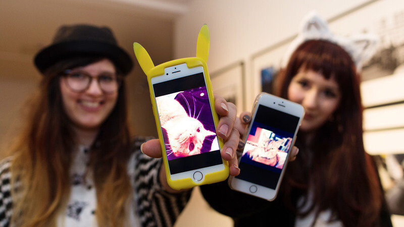 Die Festivalbesucherinnen Melisa Rexroth (r) und Jenny Kosche (l) zeigen am 19.02.2016 während des ersten deutschlandweiten Katzenvideofestivals in Düsseldorf (Nordrhein-Westfalen) Katzenfotos auf ihren Smartphones.