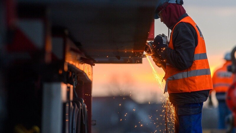 Ein Arbeiter führt auf einer Baustelle Schweißarbeiten an einer Brücke aus.