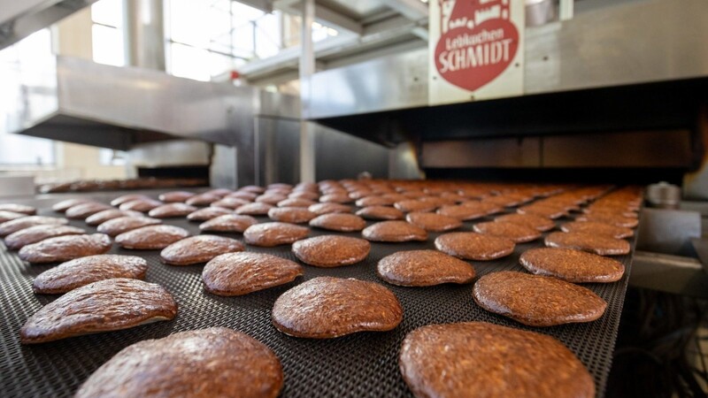 Frisch gebackene Lebkuchen laufen auf einem Band aus einem Ofen in der Produktion des Lebkuchenherstellers Schmidt.