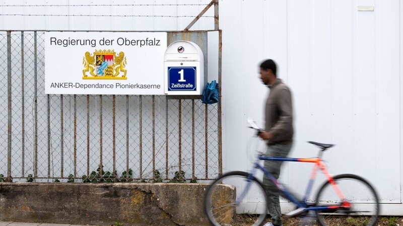 Ein Mann mit einem Fahrrad geht an einem Hinweisschild vom Ankerzentrum in der Zeißstraße vorbei.