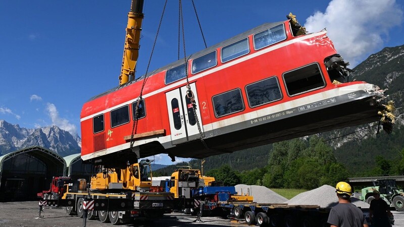 Tage nach dem Zugunglück von Garmisch-Partenkirchen gehen die Aufräumarbeiten voran. Ein auseinandergeschnittenes Waggonteil wird von einem Laster gehoben.